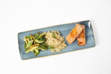 Grilled salmon fillet with quinoa and sautéed vegetables on a plate on a white background