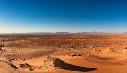 Fototapeta premium a wide open desert plain with a distant horizon where the sand and sandstone meet under a clear blue sky