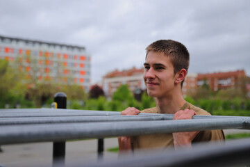 Young teenage male doing workout on sport bars, healthy lifestyle, outdoor fitness