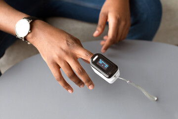 Closeup Of Pulse Oximeter Clip On Man Hand. Black Guy Measuring Oxygen Saturation Level At Home. Pulseoxymetry Medical Device, Ox And Pulse Rate Monitoring. Cropped