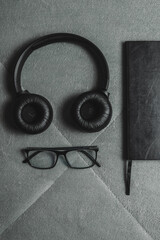 Notebook, pencil, headphones, glasses, camera, placed on a gray background.