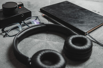 Notebook, pencil, headphones, glasses, camera, placed on a gray background.