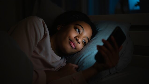 Woman using phone in bed at night scrolling social media late night mobile usage