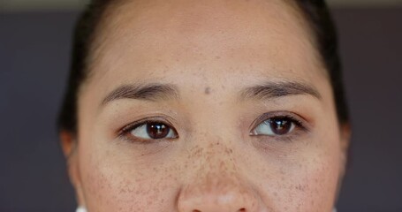 At photographer cue, Asian woman wearing pearl studs in studio blinking, shifting gaze for portrait - Powered by Adobe
