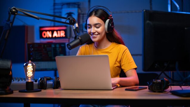 Woman podcasting live streaming online radio show using microphone and laptop at studio