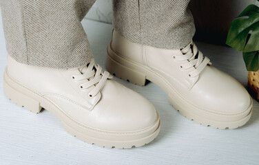 Beige boots with wool trousers on a cement background.