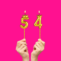 Birthday on a fuchsia background with the number 54 - Hands holding number-shaped candles