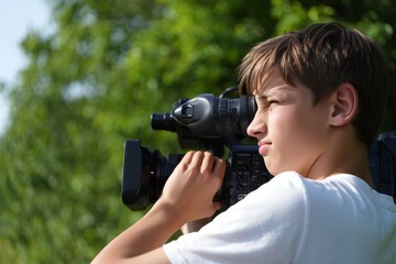 Boy filming with professional camera outdoors for video production and filmmaking work