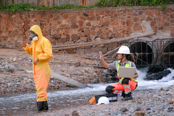 Environmental field team in protective gear analyzes water samples on a polluted beach. One holds a...