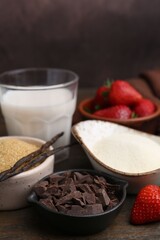 Different ingredients for panna cotta. Milk, sugar, vanilla, chocolate and strawberries on wooden table, closeup