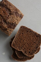 Pieces of fresh rye bread on light grey textured table, flat lay