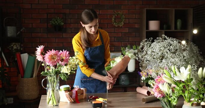 Professional florist making bouquet of flowers at wooden table in shop