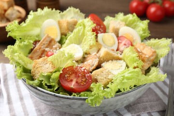 Delicious salad with croutons, chicken, quail eggs, tomato and cheese on table, closeup