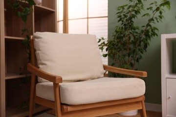 Stylish armchair near shelving unit and houseplant indoors