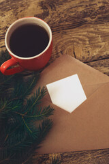 Christmas tree and red cup of aromatic coffee, Craft brown envelope and greeting card, postcard. Copy space. Rustic, retro atmospheric mood. Hardwood table, eco friendly style,
