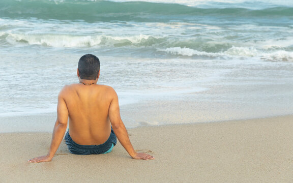 Young latin man enjoys the panoramic view to the blue sea during summer vacation time. Relaxing concept. Horizontal format. 