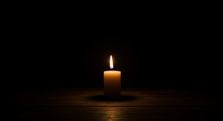 Quiet contemplation A luminous candle flame casts a soft, comforting glow in profound darkness.