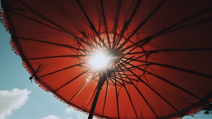 Red umbrella with sunbeams through the canopy.