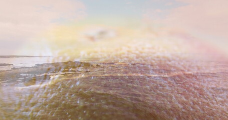 Glinting bright sun reflection dancing across water at sunrise, with rocky outcrops and ocean waves