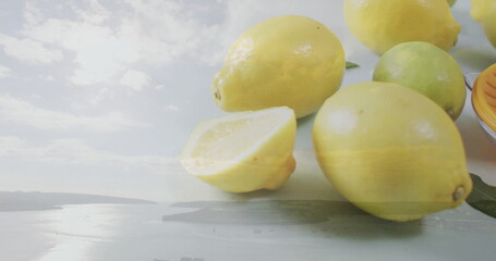Displaying close-up lemons and lime on studio tabletop, with green citrus leaves, copy space