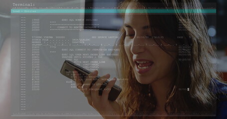 Speaking woman in dark top using smartphone in office, code overlay, blurred monitors, copy space