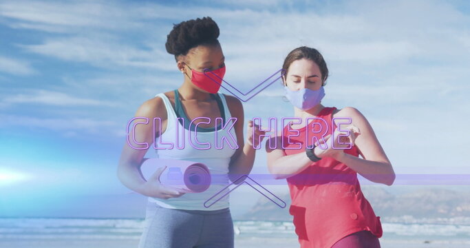 Standing women wearing sportswear and face masks on beach, holding yoga mat and checking smartwatch