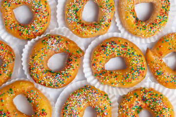 Top view flat lay of traditional Colombian roscas or donuts with colorful sprinkles, a sweet pastry...
