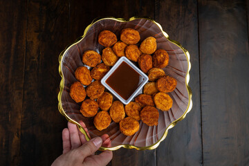 Top view of a bowl of crispy golden chicken nuggets or cheese bites served as a party food...