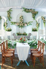 Refined Garden Wedding Stage with Floral Arches, Wooden Seating Rows, and Vibrant Red Centerpiece
