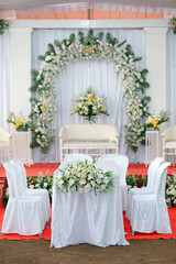 Elegant Wedding Stage with Floral Arch, White Sofa, Red Carpet, and Formal Table Setup