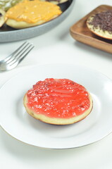 Serabi pancakes topped with strawberry jam, a traditional Indonesian snack