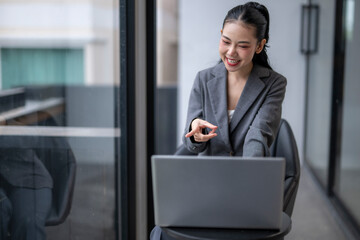 Smiling businesswoman gesturing while using laptop in office