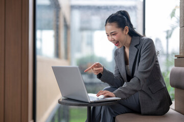 Fototapeta premium Excited businesswoman pointing at laptop screen while working remotely