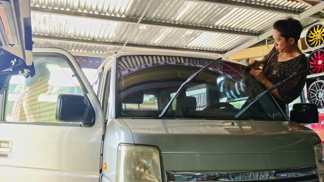 Installing window tint on a mini van in the Philippines. Handheld view.