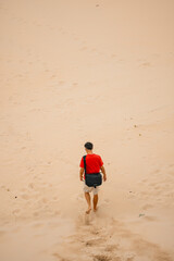 Man walking down dunes at the beach leaving a trail in the sand
