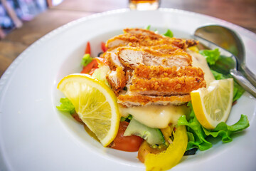 Frresh healthy vegetable salad of Lettuce, tomato, cucumber, olives, red pepper and lemon slice topped with chicken cutlets, banner, top view