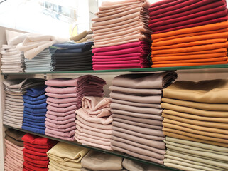 Hijab fabrics are neatly arranged on store shelves in a variety of colors. Satin, cotton, and silk fabrics are displayed on shelves, arranged by color and gradation. Muslim women's fashion. Copy space