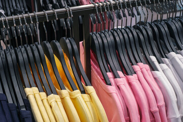 Knitted sweaters hang on wooden hangers in clothing store.