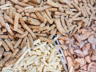 Top angle shot of frozen fried food. Frozen food consisting of French fries, chicken strip nuggets, and fish cakes. Half-cooked instant food sold in supermarkets. Food ingredients backgrounds