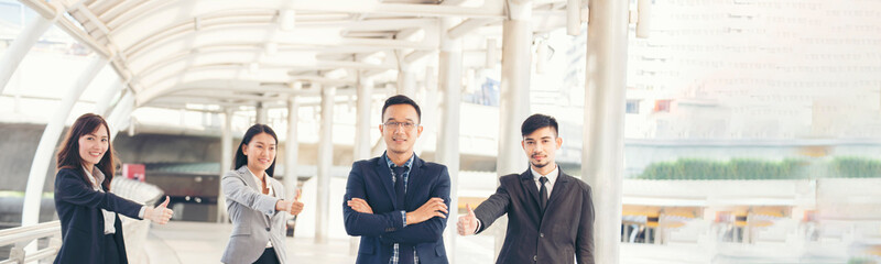 Banner Portrait Group of businesspeople arms crossed smiling look at camera in modern city background. Banner Happy teams partnership. Business people teams positive teamwork standing with copy space