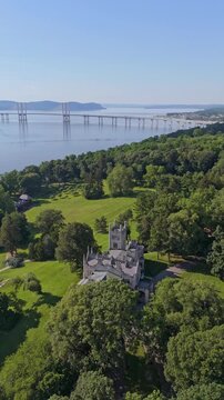 Drone orbits Lyndhurst Mansion in Tarrytown, NY, revealing the Hudson River and Governor Mario M. Cuomo Bridge in background. Panoramic aerial