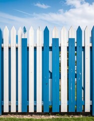 Obraz premium Blue and white picket fence against a bright blue sky