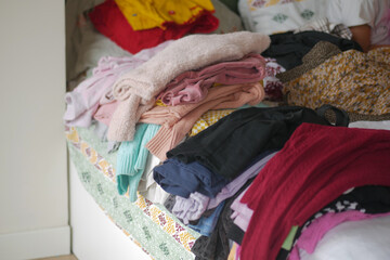 Pile of freshly folded laundry on a neatly made bed