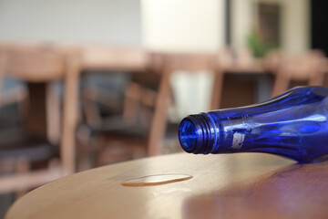 Empty blue bottle on a wooden table in a quiet cafe