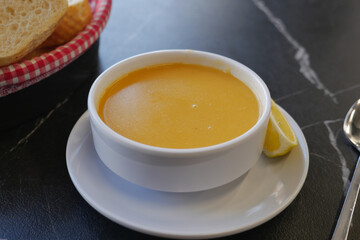 Creamy soup served with lemon wedge and bread basket