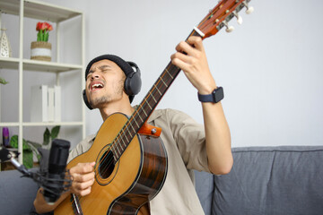 Obraz premium Male Musician Enthusiastically Performing Song Recording Music In Home Studio