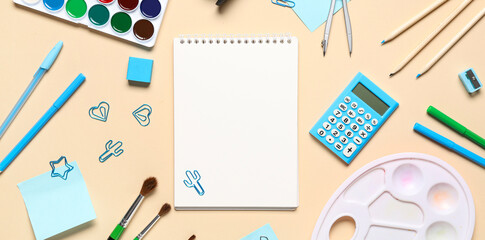 Paint palette, watercolor paints and different stationery on beige background