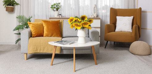 Interior of stylish living room with sofa and sunflowers on coffee table