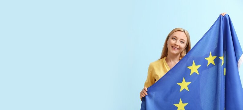 Mature woman with flag of European Union on light blue background with space for text
