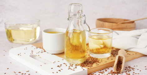 Bottle, glasses with flax oil and seeds on light background